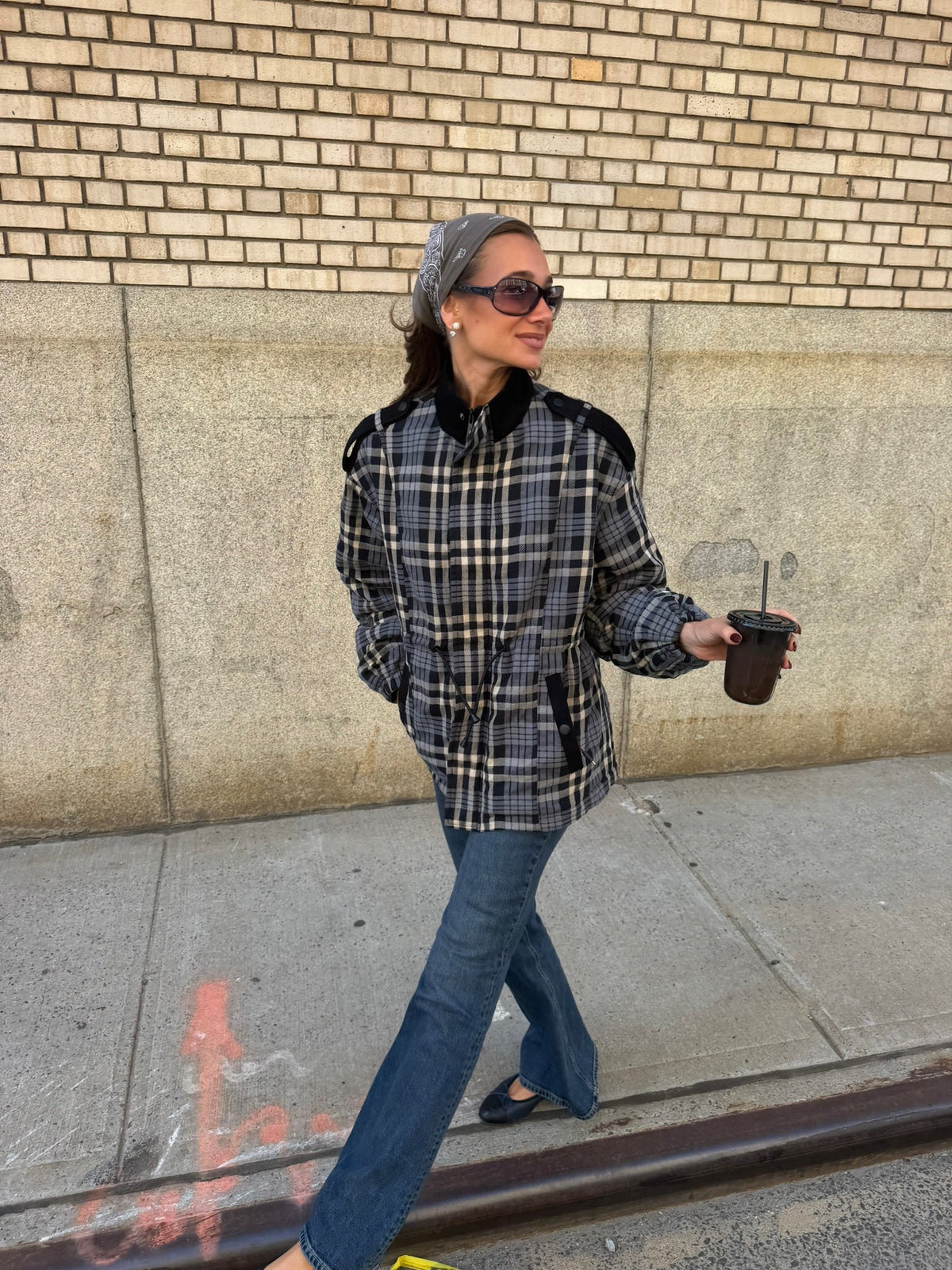 WeWoreWhat Danielle Bernstein outside on the sidewalk with coffee in her hand wearing the Cinched Waist Funnel Neck Jacket with medium wash jeans 