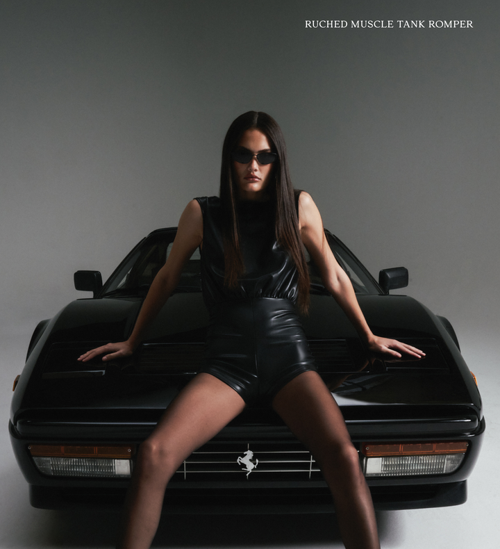 Woman in black outfit sitting on a black Ferrari, with text 'Ruched Muscle Tank Romper' at the top.