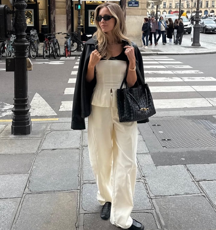 Woman standing outside on sidewalk in Paris wearing WeWoreWhat white and black corset top with matching balloon trousers 