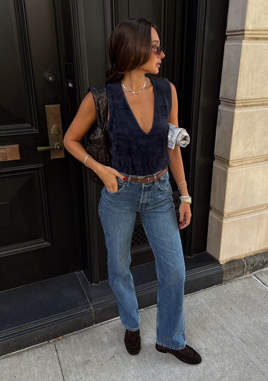 Danielle Bernstein wearing new navy sweater vest standing outside on sidewalk with a black door background